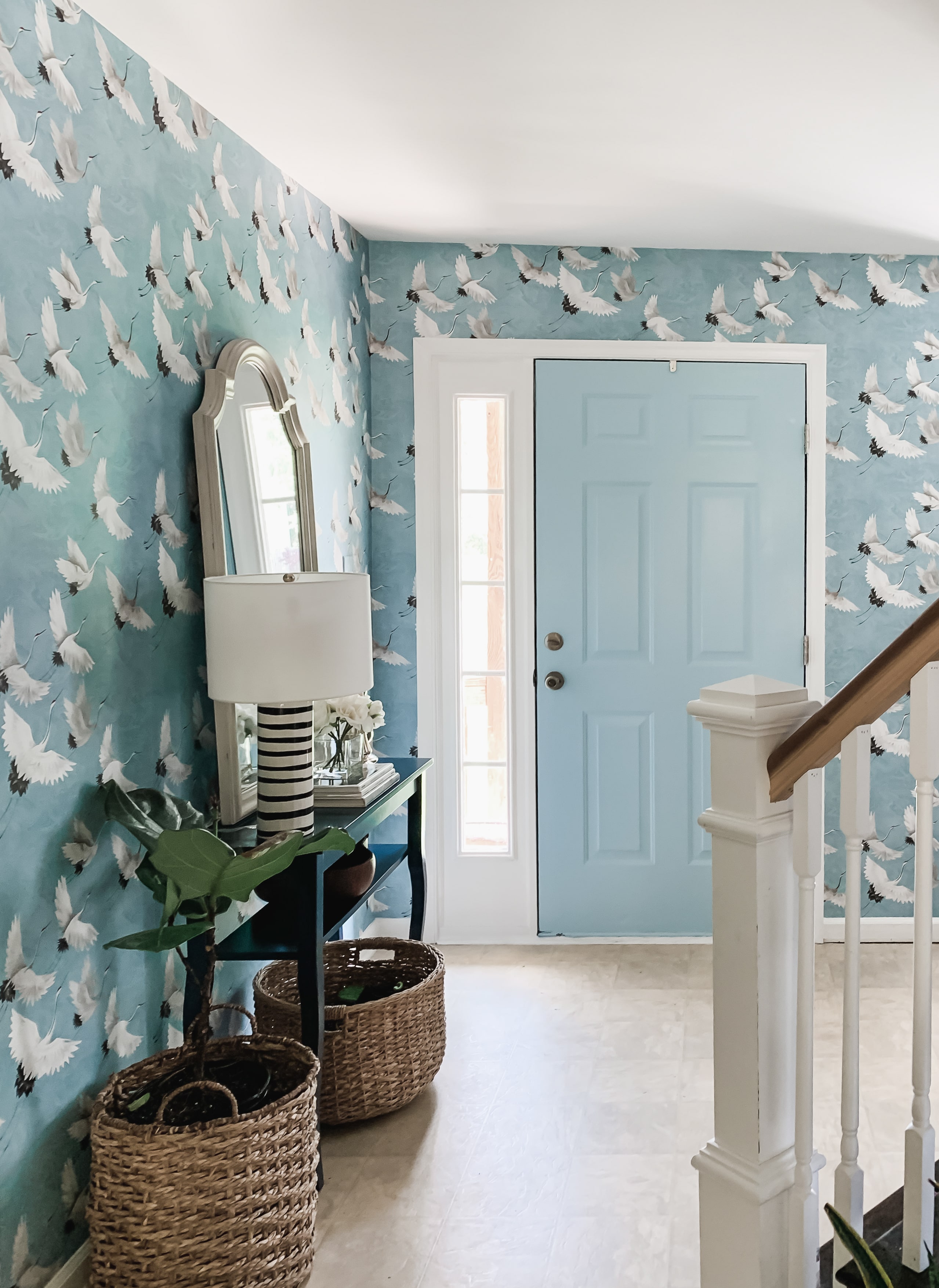 Bold, blue crane wallpapered entryway design with Sherwin Williams Stream painted door