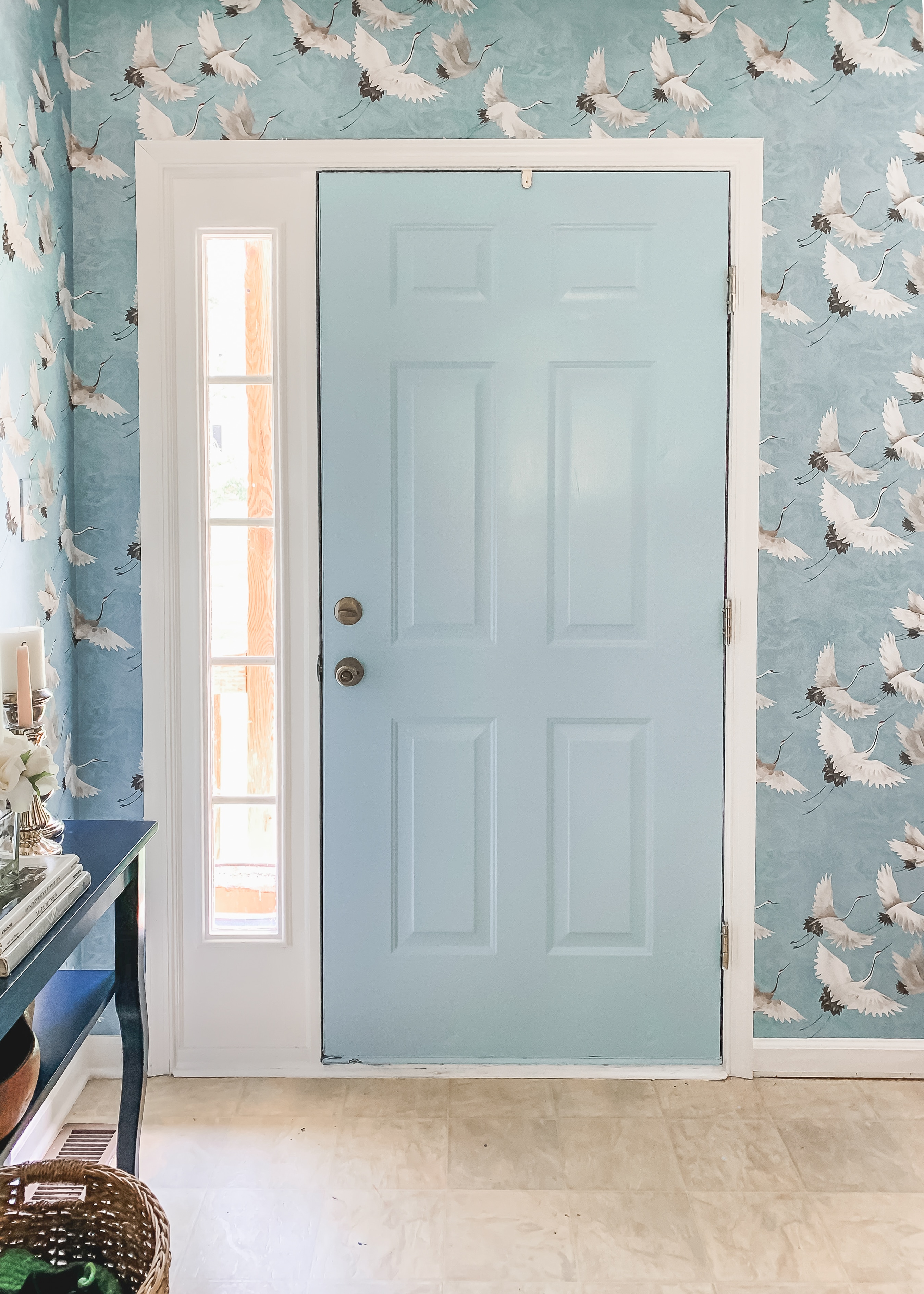 Bold, blue crane wallpapered entryway design with Sherwin Williams Stream painted door