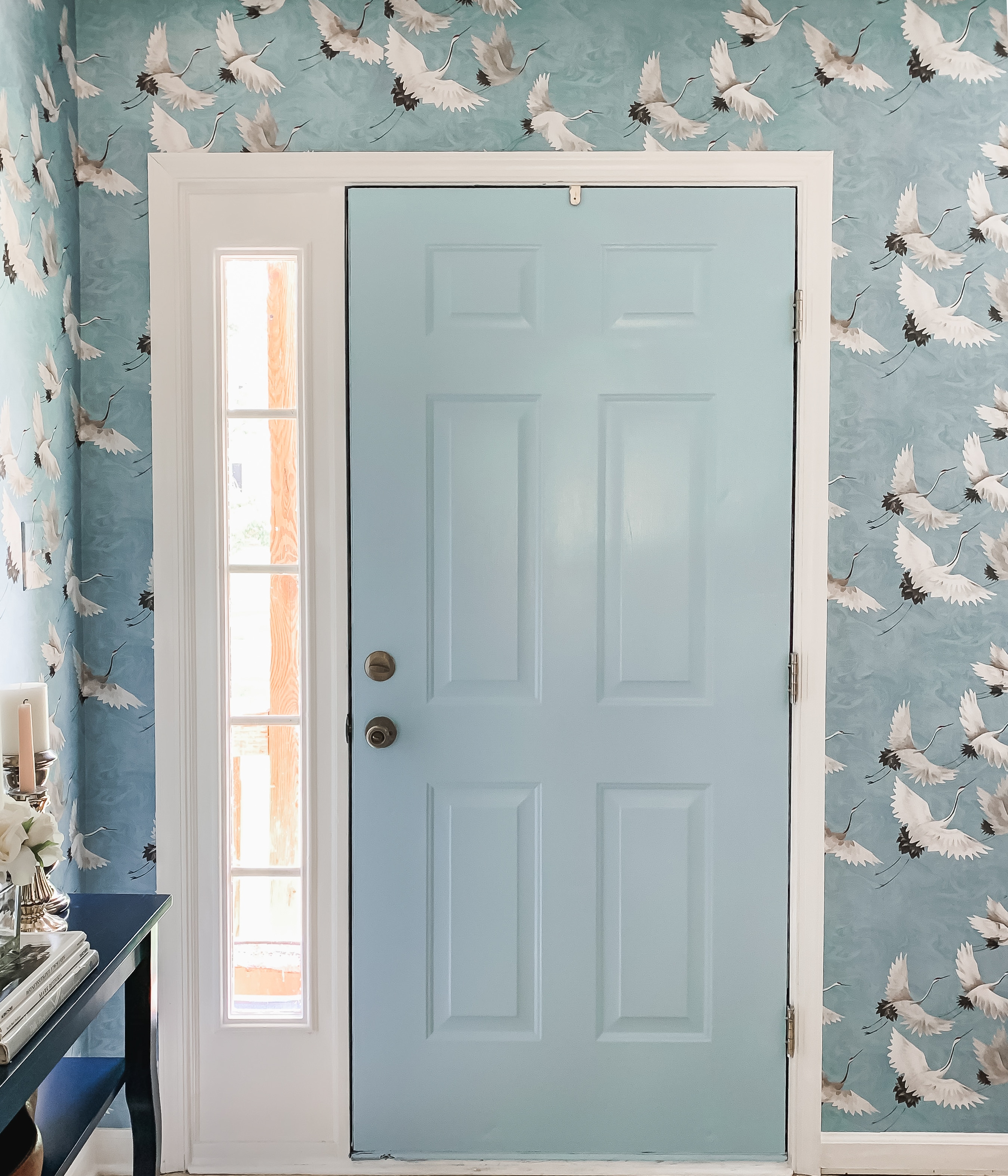Bold, blue crane wallpapered entryway design with Sherwin Williams Stream painted door