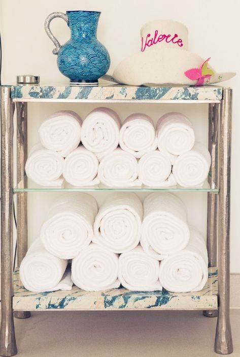 Roll white towels and stash them on a bar cart for ideal bathroom storage