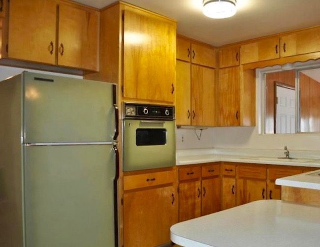 This image has an empty alt attribute; its file name is classic-70s-hideous-kitchen-featuring-avocado-green-fridge-oven-orange-cabinets.jpeg