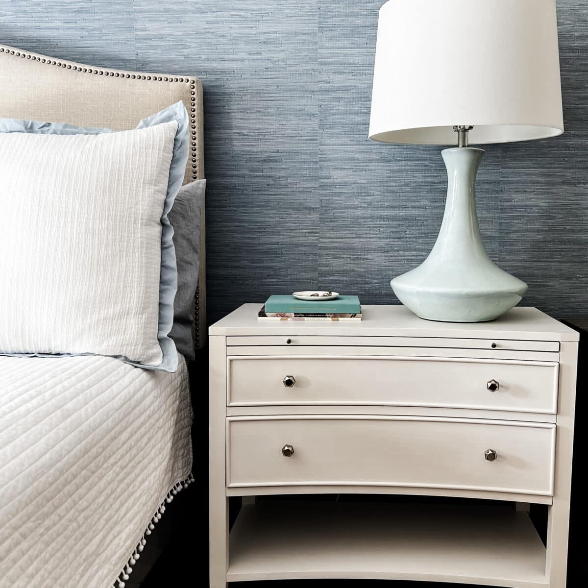 traditional white night stand with blue grasscloth wallpaper